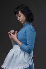 Naklejka premium Gothic-style woman in blue Victorian dress with apron, Alice in Wonderland theme