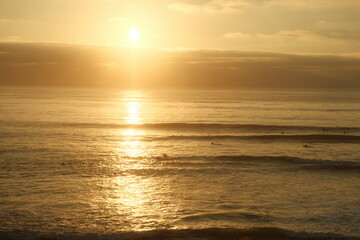 Beautiful yellow orange sunset over ocean in sunset cliffs ocean beach with surfer silhouettes in san diego california