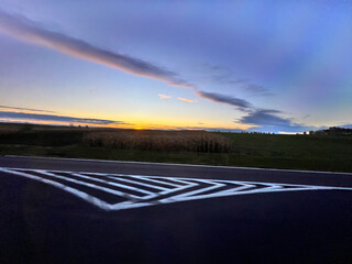 Road marking with sunset over cornfield and rural landscape