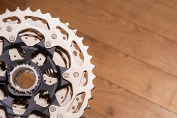 Close up of a multi sprocket rear cassette mounted on a bicycle hub, partially visible on wood background