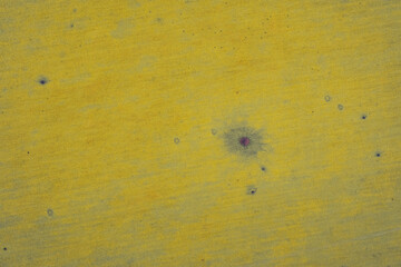 Top-down aerial photograph capturing vivid yellow agricultural texture. A small dark anomaly, spot creates a visual focal point on the uniform crop field, illustrating potential disease or soil defect