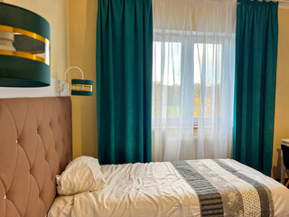 Hotel room interior with unmade bed and green curtains