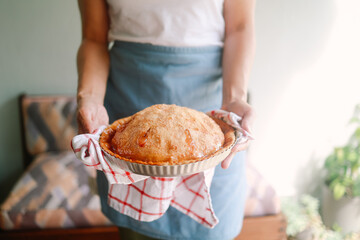 Woman holding freshly baked apple pie in home kitchen for thanksgiving celebration. Holiday preparation dessert