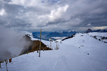 Snow-dusted Hoch-Ybrig ridge frames a dramatic Swiss Alps scene under a brooding sky.