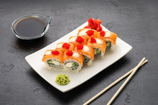Salmon sushi rolls with cream cheese, red roe, soy sauce, wasabi and ginger, top view