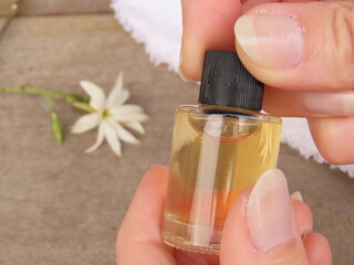 Closeup of woman hands opening a small bottle of hair oil. Self-care and wellness concept. 