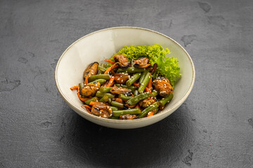 Mussel and green bean salad with sesame in a ceramic bowl on dark stone