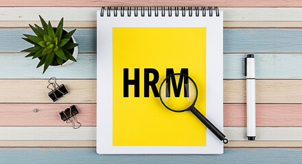 Hrm concept displayed on a notepad with a magnifying glass and pen on a colorful wooden desk for business and human resources