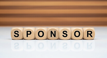 Wooden blocks spelling sponsor on a white surface with a blurred wood background for business partnership and financial support concepts