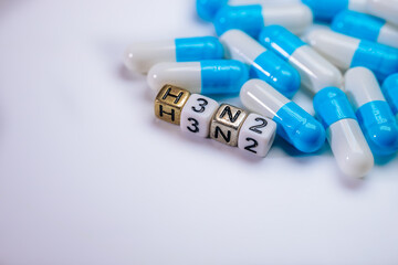 Blue and white capsules scattered on a surface, with lettered blocks displaying H3N2, representing pharmaceutical concepts and health-related themes in a vibrant composition