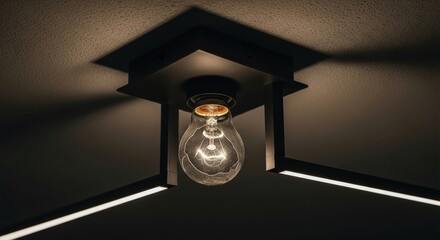 Close up of cracked glass light bulb glowing inside modern black metal geometric cage ceiling fixture with dramatic shadows on dark background