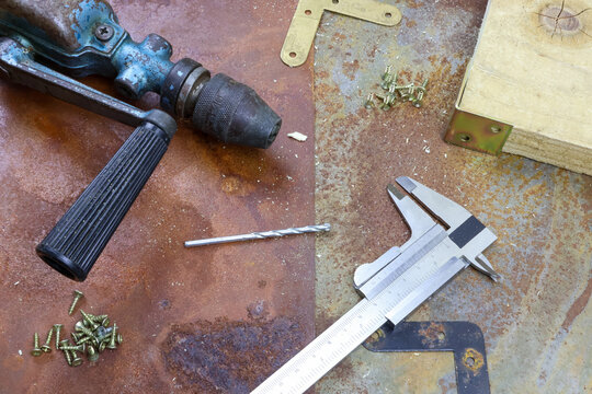 Vintage woodworking tools rusty table old hand drill metal chuck black handle a vernier caliper. industrial feel complementing aged appearance of the tools. workshop focused on traditional handcraft