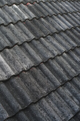 Weathered grey corrugated roof tiles. Close-up of aged textured surface showing dirt, moss, and discolored patterns. Ideal for backgrounds.