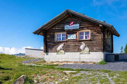 Stans, Switzerland - July 10, 2025: A charming wooden mountain hut at Stanserhorn with a sign HEIDI, surrounded by lush green grass and a clear blue sky