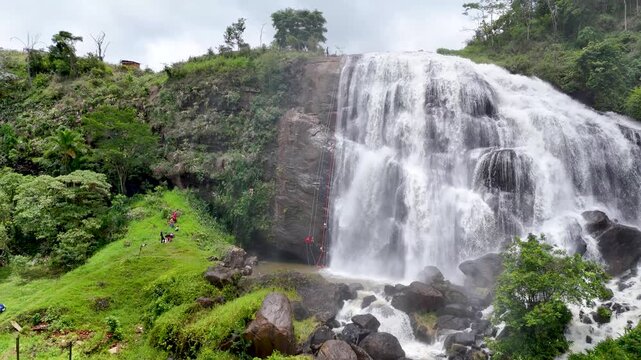 Aerial scene of a zoom-out clip of people abseiling in a waterfall in Minas Gerais, Brazil