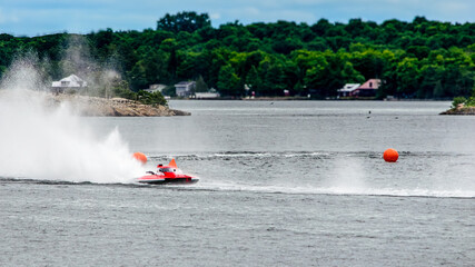 Red and white racing boat speeding around two orange bouys
