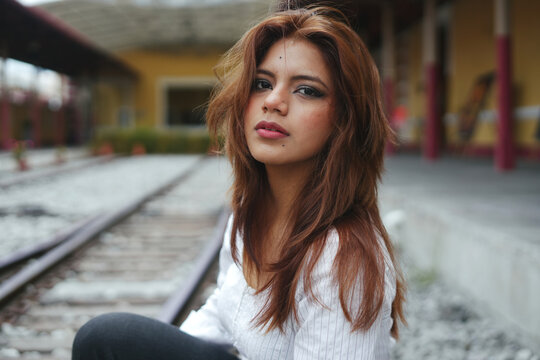 Young woman with readhead hair posing at train station.World Fashion Day