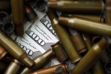 Many US dollar bills details seen through big amount of used cartridges