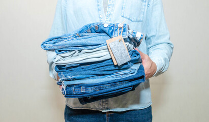 Handsome young happy man arranging stylish jeans in dressing room.