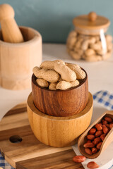 Bowls and scoop with fresh peanuts on light wooden table