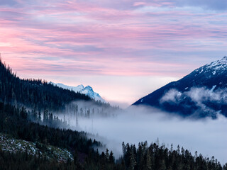 Obraz premium Sunset Over Frosty Valley: Misty Forests and Snow-Capped Mountains in BC, Canada