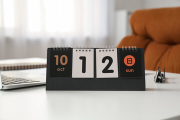 Flip calendar with date 12 OCTOBER on desk in office, closeup
