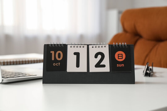 Flip calendar with date 12 OCTOBER on desk in office, closeup