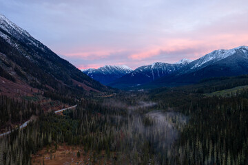 Valley Scene With Snowy Peaks And Pink Sunset In BC, Canada—Forested Canyon And Mountain Ridge