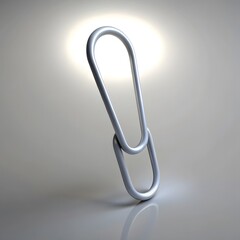 A single silver paperclip standing upright on a light gray surface with a spotlight overhead