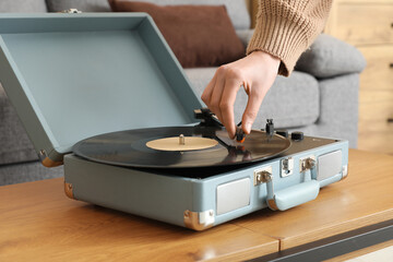 Young woman using retro record player in living room, closeup