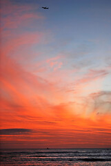 Airplane flying in spectaculaer sunset sky over Waikiki beach in Honolulu, Hawaii