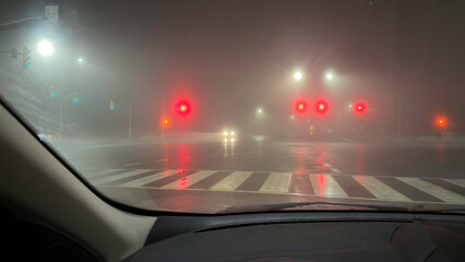 Road intersection at rainy night as seen from a car driver's point of view