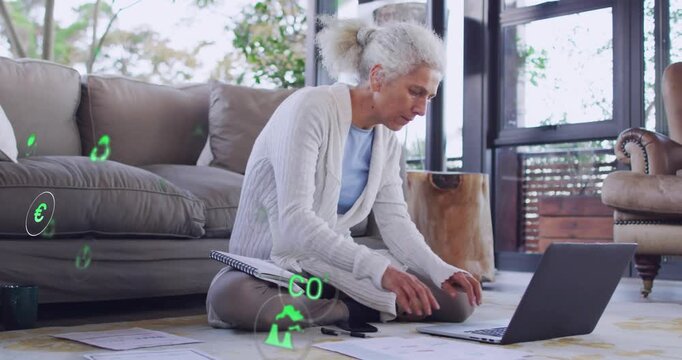 Woman writing notes reaching phone shifting to laptop doing energy plan with green icons overlaying