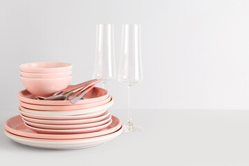 Clean glasses with plates, bowls and cutlery on white background