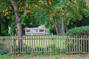 Green meadow with wooden fence and parked campers beyond