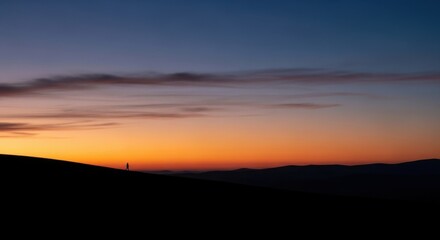 Fototapeta premium Sunset over the mountains with a vibrant orange and blue sky.