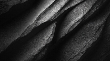 Fototapeta premium A textured black surface with dramatic light and shadow, showcasing wavy patterns and depth, creating a striking and abstract visual.