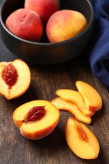 Wooden board and bowl with sweet ripe peaches on black background, closeup