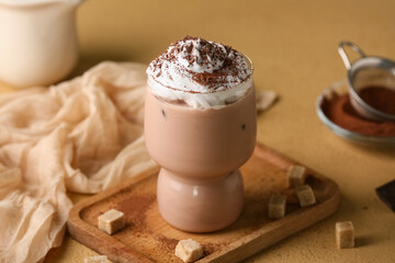 Glass of cocoa drink with whipped cream and sugar cubes on brown background