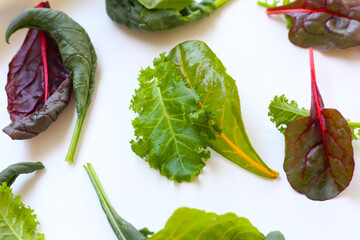 Mixed of fresh vegetable green leaves, including green kale and red-veined chard, spinach on white background.