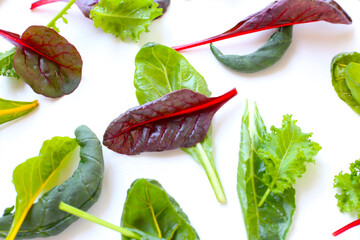 Mixed of fresh vegetable green leaves, including green kale and red-veined chard, spinach on white background.