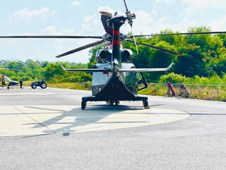Helicopter Parked on Helipad with Green Forest Background
