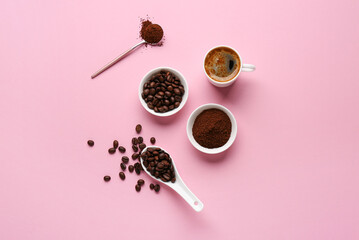 Cup of coffee with beans and powder on pink background