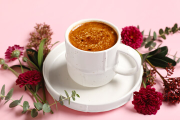 Cup of coffee with chrysanthemum flowers and eucalyptus branches on pink background