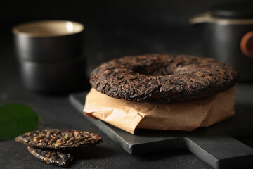 Board with dry pressed puer tea on black grunge background