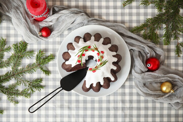 Obraz premium Tasty cut Christmas cake with spatula, candle, balls and fir tree branches on table
