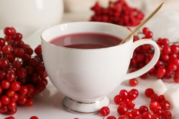 Cup of hot viburnum tea with sugar cubes, closeup