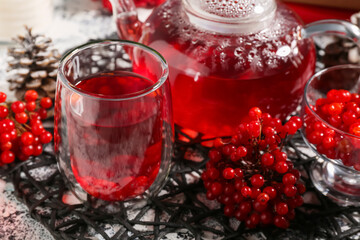 Glass cup and teapot of hot viburnum tea on grey grunge background