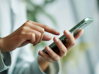 スマホを操作する女性の手元　A close-up of a woman's hands operating a smartphone　Generative AI