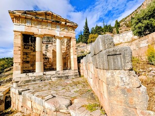 Ancient greek Athenian Treasury in Delphi, Greece. UNESCO archaeological ruins with myth and rich heritage at the Temple of Apollo where travelers go to pray to the oracle.